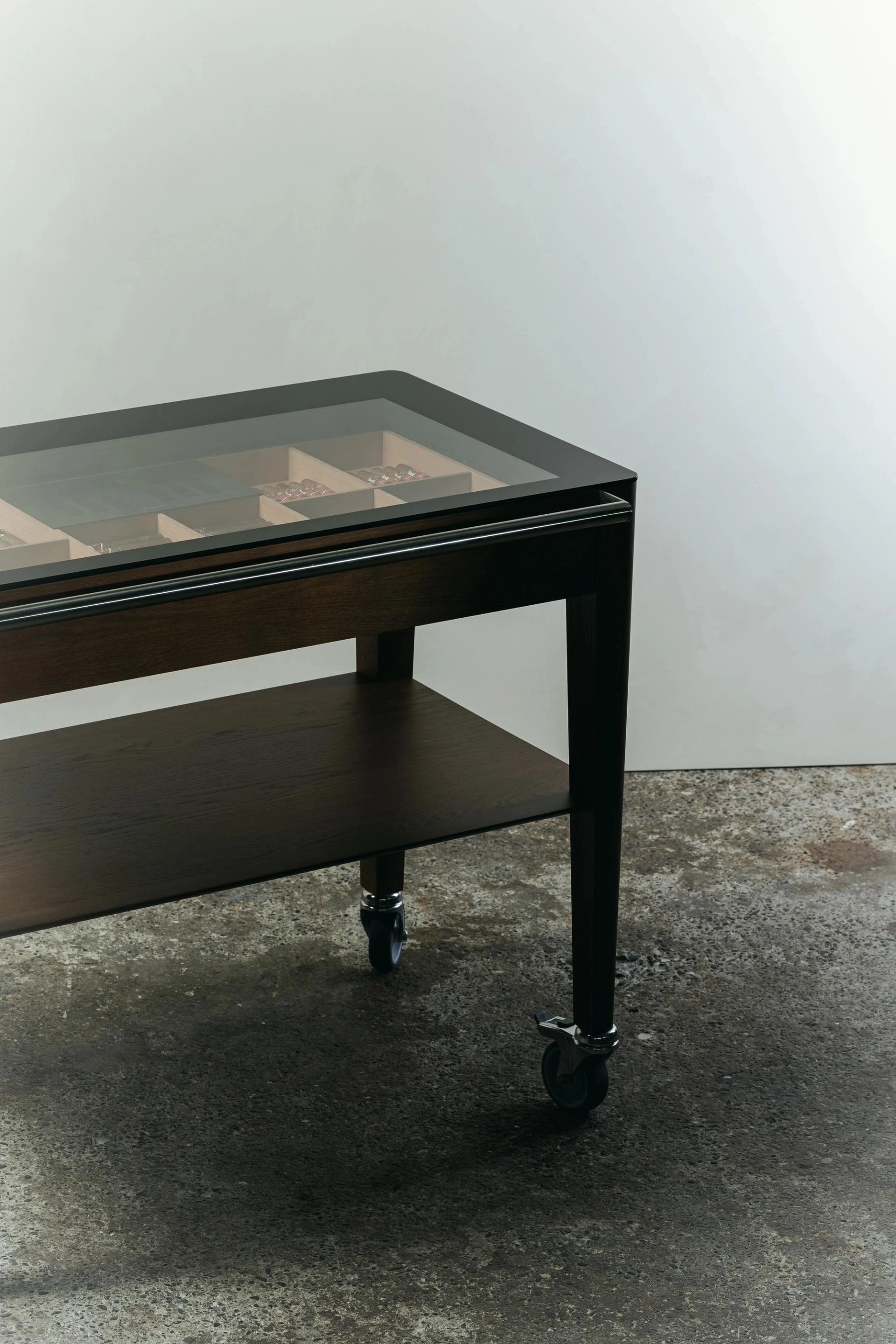 Chariot à cigare en chêne de Bourgogne teinté avec un plateau en verre, un tiroir à cigares, une étagère inférieure et une poignée en acier inoxydable, monté sur quatre roulettes.